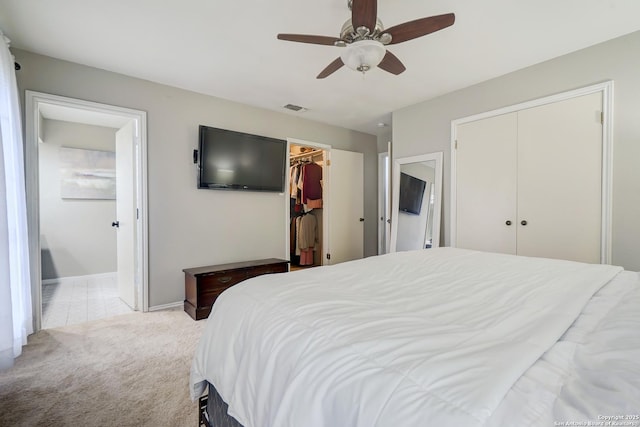 bedroom with visible vents, baseboards, light colored carpet, connected bathroom, and a ceiling fan