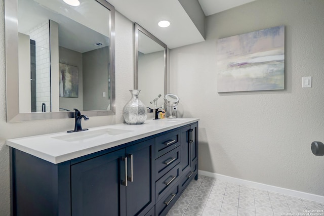 bathroom featuring double vanity, baseboards, a sink, and tile patterned floors