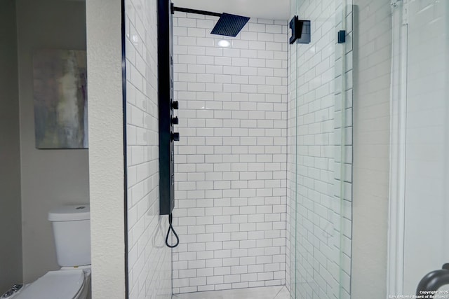 bathroom featuring toilet and a shower stall