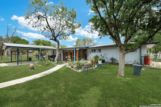 back of house featuring a sunroom, a lawn, fence, and brick siding