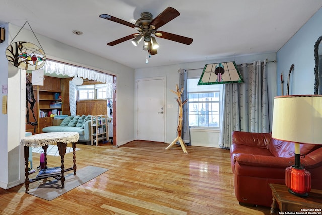 living area with baseboards, ceiling fan, and wood finished floors