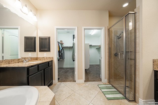 full bath with a shower stall, vanity, baseboards, tile patterned floors, and a spacious closet