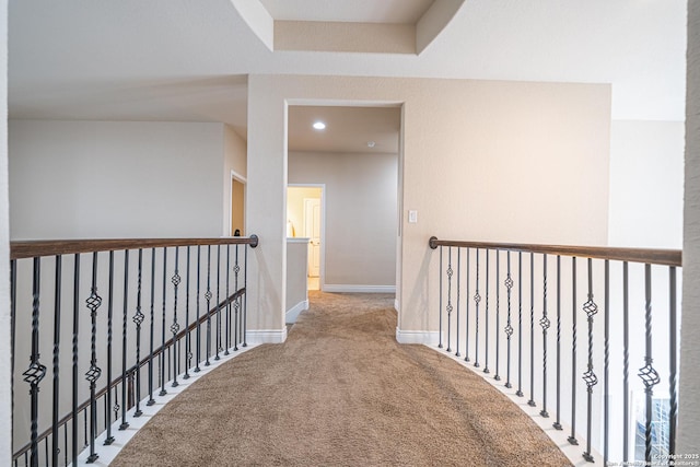 hallway featuring baseboards, an upstairs landing, and carpet