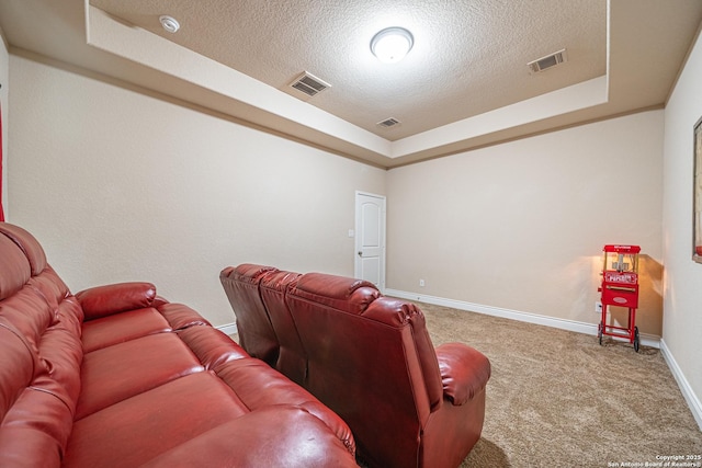 cinema with a textured ceiling, visible vents, carpet floors, baseboards, and a tray ceiling