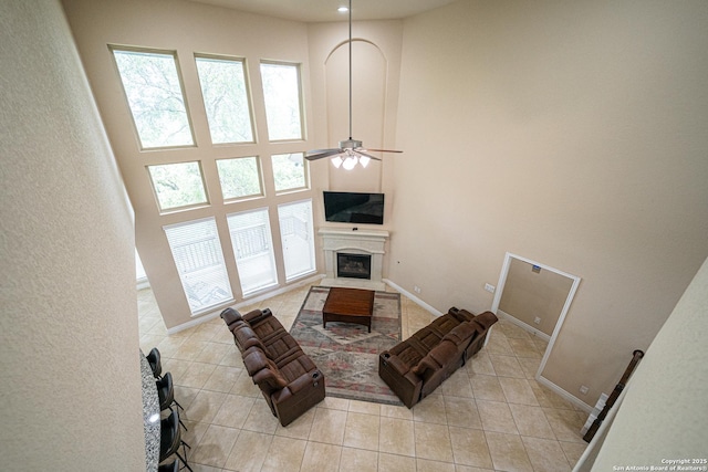 living area with a ceiling fan, a high ceiling, a wealth of natural light, and a fireplace