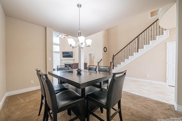 tiled dining area featuring a fireplace, baseboards, a notable chandelier, carpet, and stairs