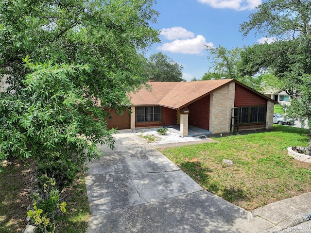 view of front of house featuring brick siding, a shingled roof, driveway, and a front yard