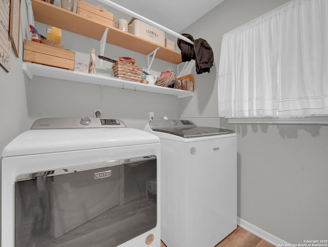 laundry area with baseboards, laundry area, washing machine and dryer, and wood finished floors