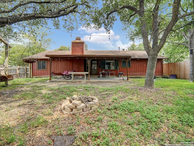 rear view of property with a patio area, a fire pit, fence, and a chimney