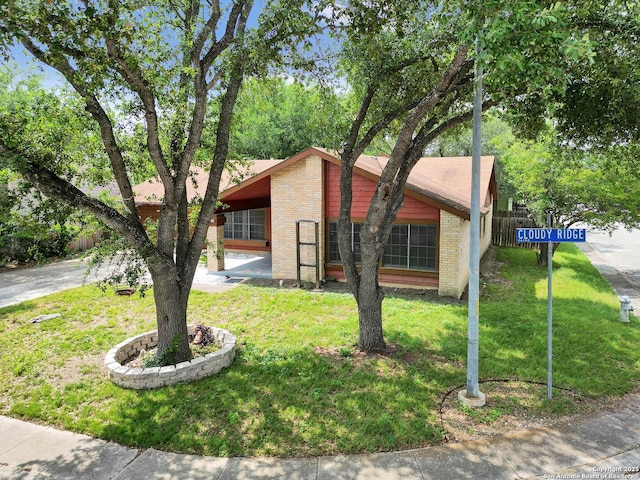 view of front facade featuring brick siding, fence, and a front yard