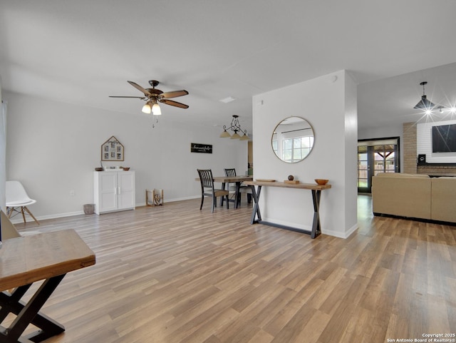 living room featuring baseboards, a ceiling fan, and light wood finished floors