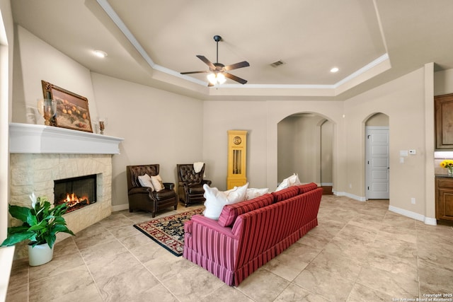 300 Knoll Spgs, Boerne, TX 78006 - living room featuring ceiling fan, a stone fireplace, crown molding, arched walkways, and a tray ceiling