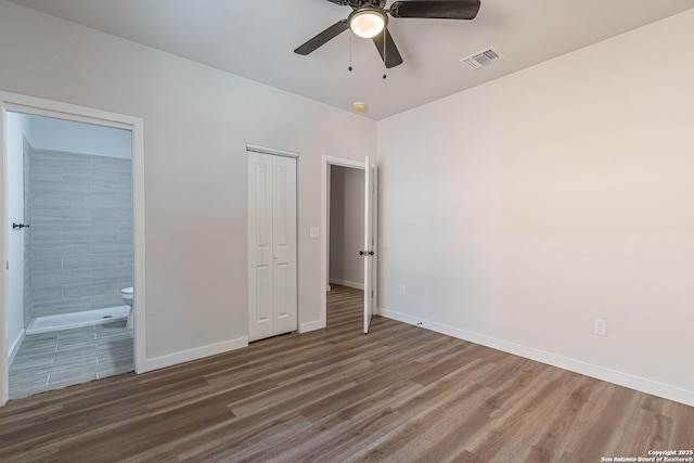 unfurnished bedroom with visible vents, wood finished floors, baseboards, a closet, and ensuite bathroom
