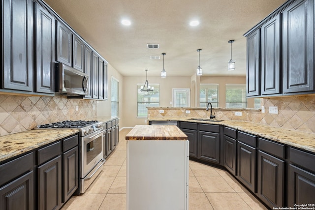 kitchen with visible vents, a peninsula, butcher block counters, a sink, and stainless steel appliances