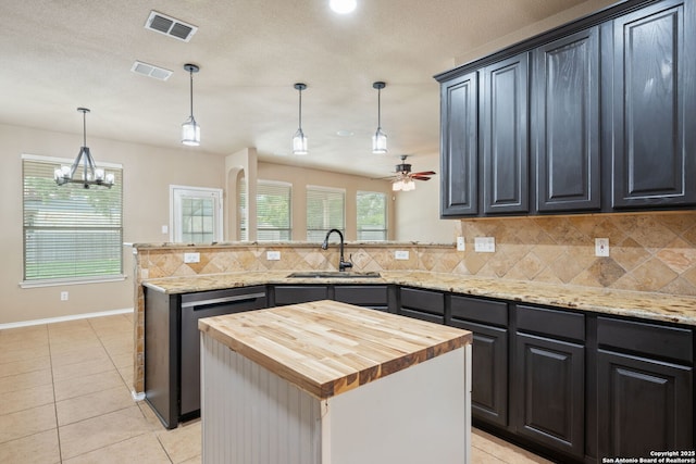 kitchen featuring visible vents, butcher block countertops, tasteful backsplash, a sink, and ceiling fan with notable chandelier
