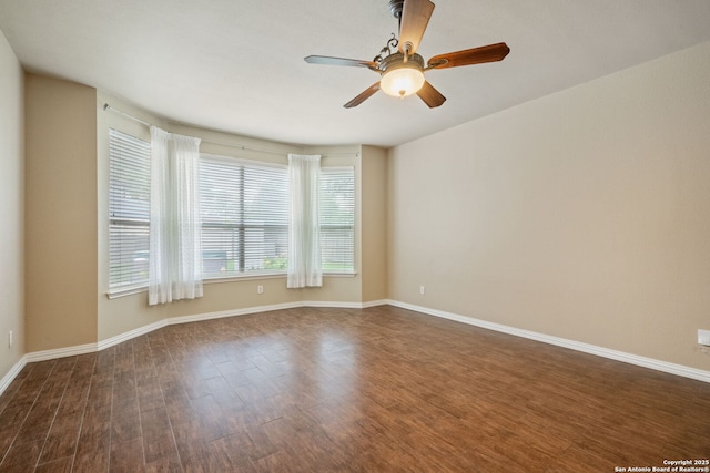 spare room featuring baseboards, ceiling fan, and dark wood-style floors