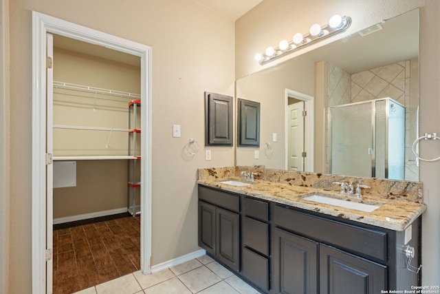 bathroom with a sink, baseboards, a shower stall, and a walk in closet