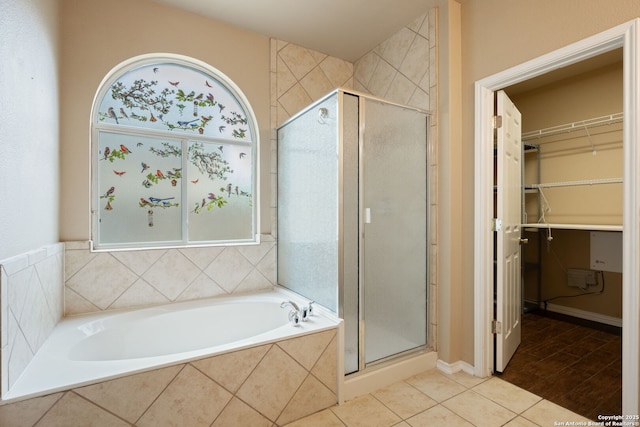 bathroom with a walk in closet, a shower stall, a wealth of natural light, and a bath