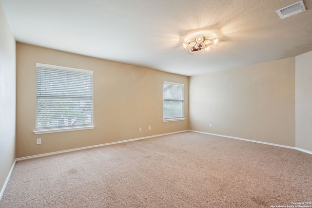 empty room featuring plenty of natural light, carpet, and visible vents