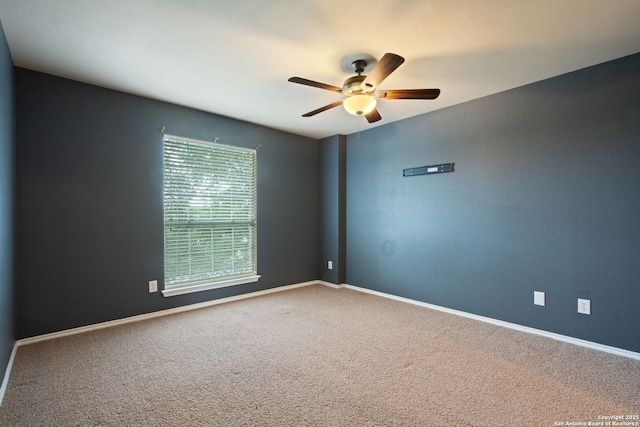 empty room with carpet flooring, a ceiling fan, and baseboards