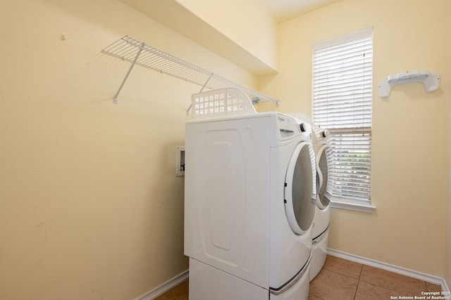 laundry room with laundry area, baseboards, tile patterned floors, and washing machine and clothes dryer