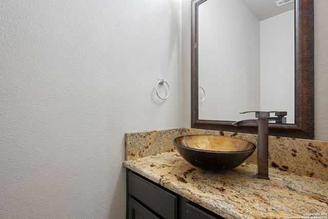 bathroom featuring a textured wall and vanity