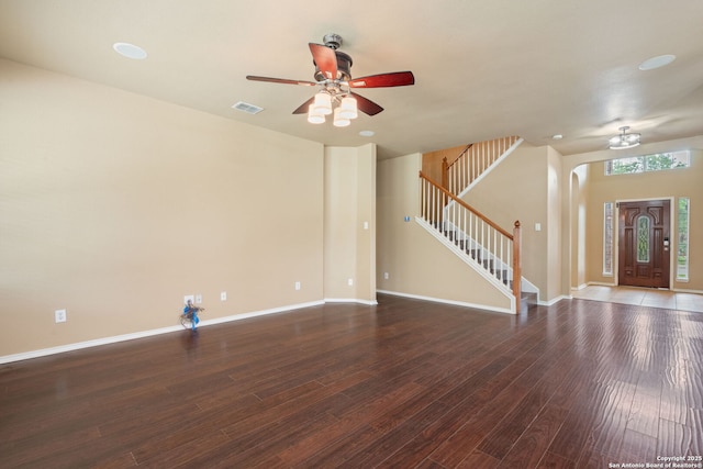 unfurnished living room featuring ceiling fan, visible vents, wood finished floors, baseboards, and stairs