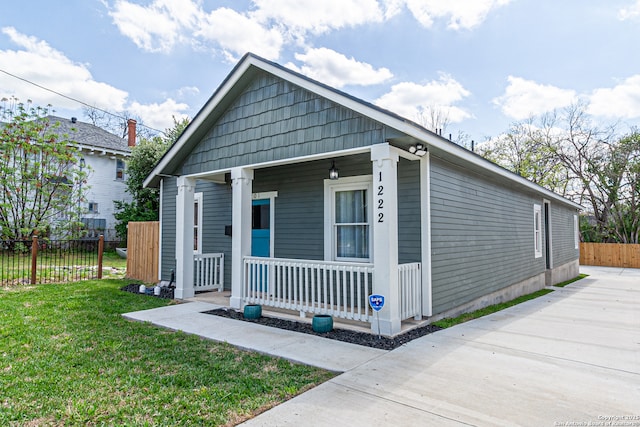view of front of house with a porch, fence, and a front yard