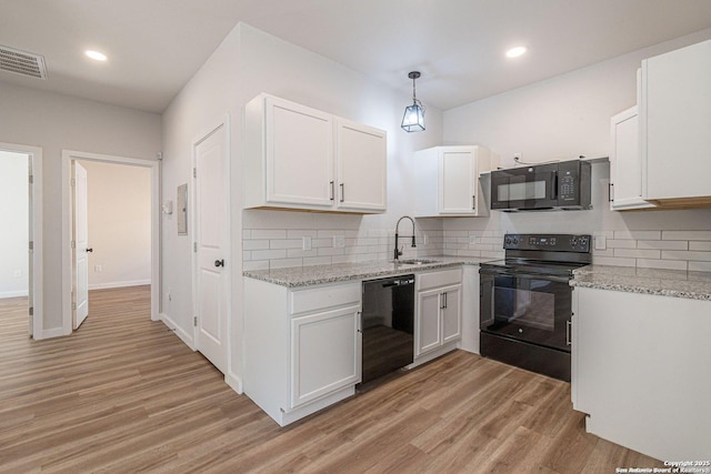 kitchen featuring a sink, black appliances, light wood-style flooring, and visible vents