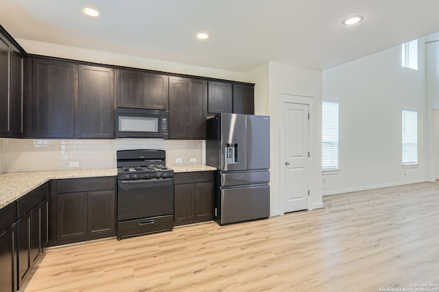 kitchen with dark brown cabinets, light wood finished floors, black appliances, and tasteful backsplash