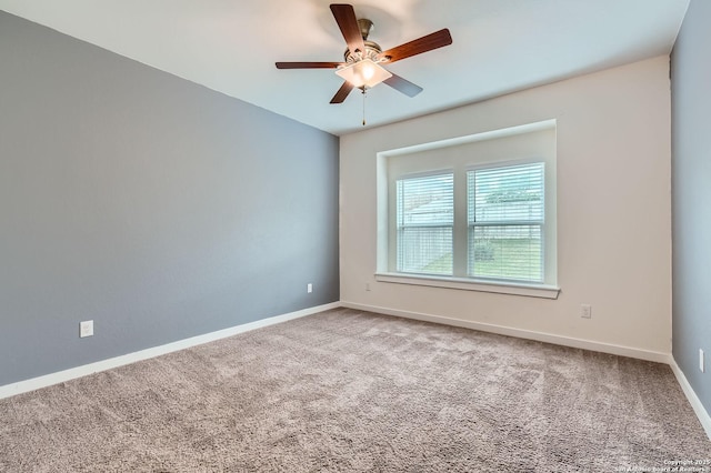 carpeted spare room with ceiling fan and baseboards