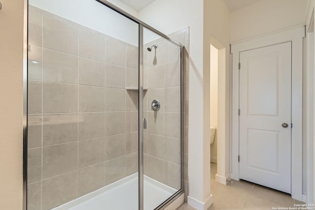 bathroom with tile patterned flooring, baseboards, a stall shower, and toilet