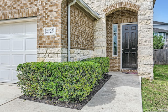property entrance featuring brick siding, a garage, and stone siding