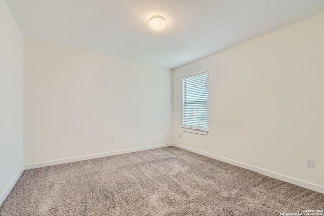 spare room featuring baseboards and light colored carpet
