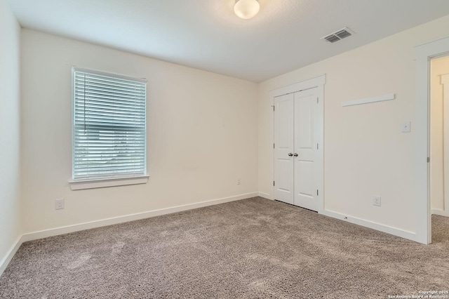 unfurnished bedroom featuring baseboards, carpet, a closet, and visible vents