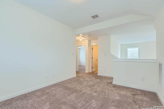 carpeted empty room with visible vents, attic access, baseboards, and rail lighting