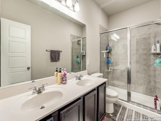 bathroom with toilet, a shower stall, and a sink