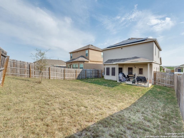 back of property featuring a lawn, a fenced backyard, roof mounted solar panels, and a patio area