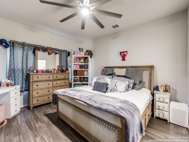 bedroom featuring a ceiling fan, visible vents, and wood finished floors