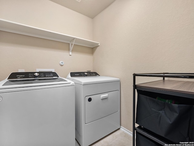 washroom featuring laundry area, light tile patterned floors, and washing machine and clothes dryer