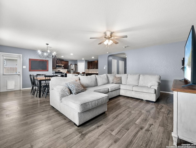 living area featuring dark wood-style flooring, arched walkways, baseboards, ceiling fan with notable chandelier, and recessed lighting