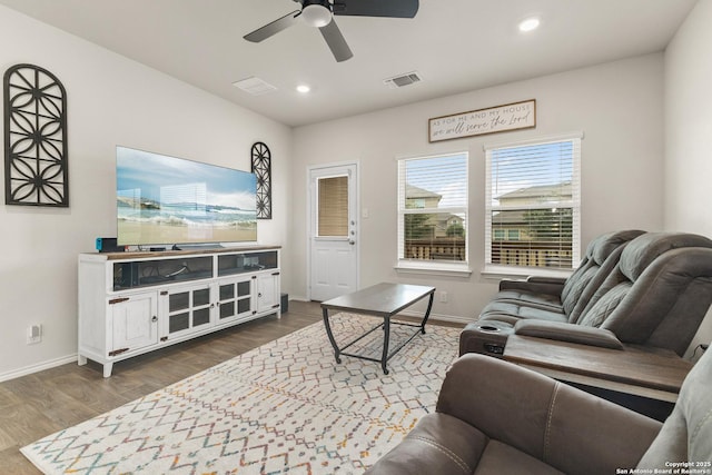 living area featuring dark wood-style flooring, a ceiling fan, baseboards, and visible vents