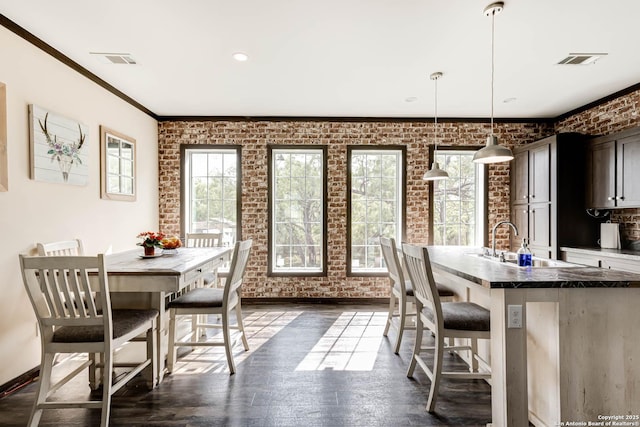 kitchen with visible vents, a sink, brick wall, and a kitchen bar