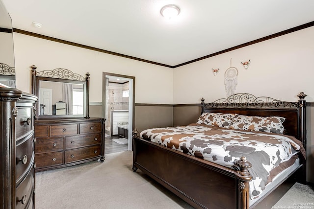 bedroom with ensuite bathroom, ornamental molding, light carpet, and wainscoting
