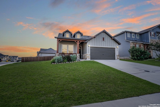 view of front of house with board and batten siding, an attached garage, fence, and a front yard