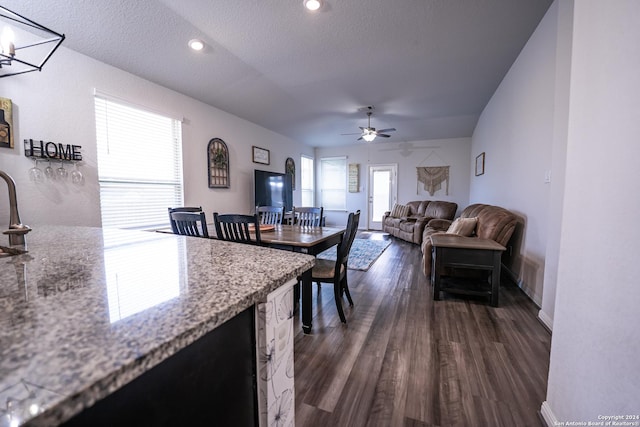 interior space featuring ceiling fan, dark wood-style flooring, a textured ceiling, light stone countertops, and baseboards