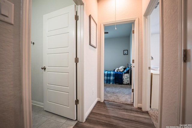 hallway featuring baseboards, attic access, and wood finished floors