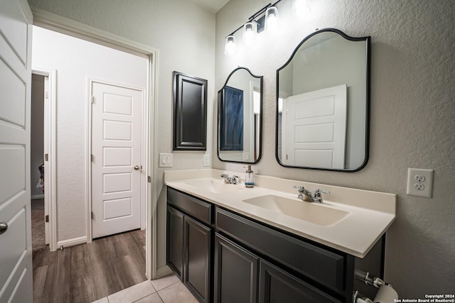 full bath with double vanity, a sink, and a textured wall