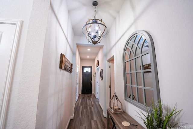 hall with dark wood-type flooring and a chandelier
