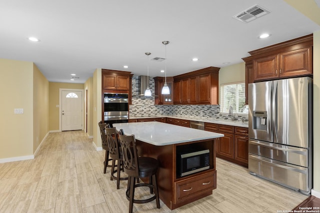 kitchen featuring wall chimney range hood, light countertops, stainless steel appliances, backsplash, and visible vents